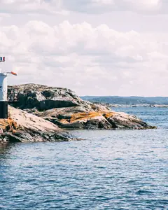 Liten fyr på klipporna vid havet en solig sommardag