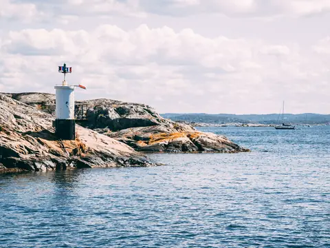 Liten fyr på klipporna vid havet en solig sommardag